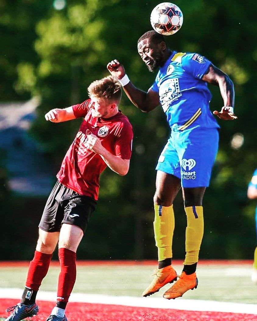 Two soccer players competing for a header during a match